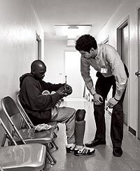 One of two coordinators at MEDiC’s Grace clinic during spring 2009, Michael DeVita ’06, MDx’11, at right, leans down to talk with a patient who lost his lower leg to frostbite. DeVita keeps things running smoothly at the clinic, directing the other medical students and stepping in as needed to care for patients.