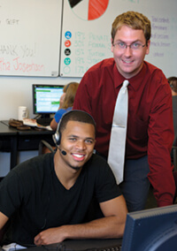 Brad Green, assistant director of annual giving at the UW Foundation (standing), here with Telefund student Marcus Cromartie x’12, says callers enjoy their conversations with alumni. Photo: James Gill