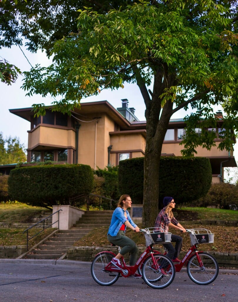 Two bicyclists ride past Frank Lloyd Wright house