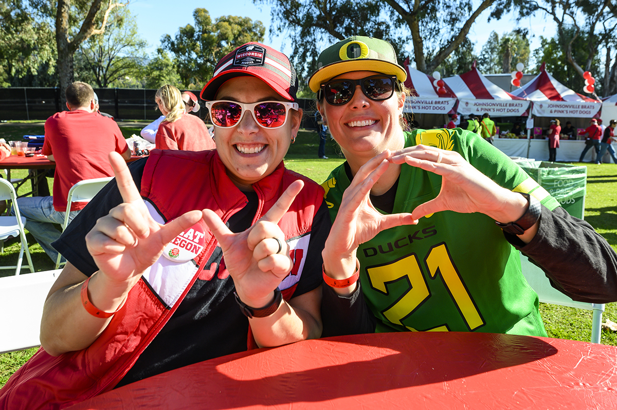 Badger fan Megan Rollo and her wife, an Oregon fan, Jordan Wilde make the Wisconsin "W" and Oregon "O" hand signs