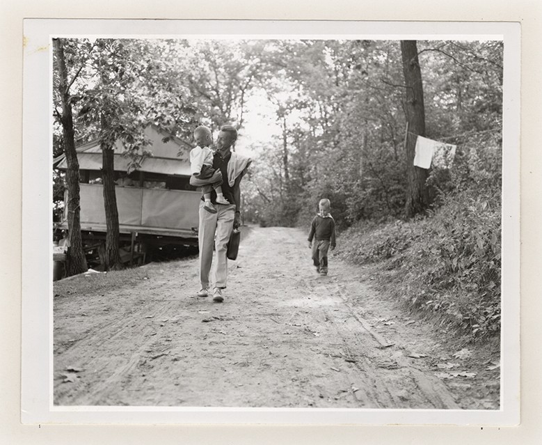 Black and white polaroid of campers walking along a wooded path
