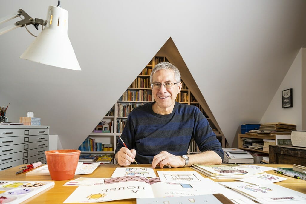 Kevin Henke at his desk with his illustrations