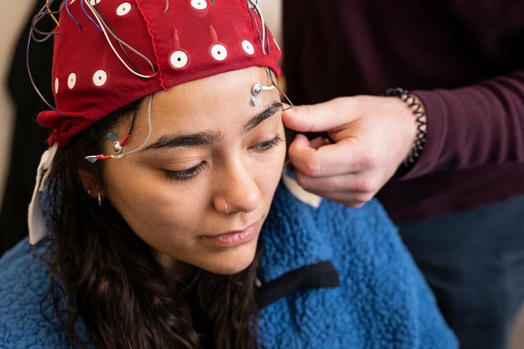Woman wearing cap fitted with facial muscle sensors