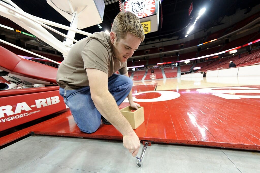 Staff members at the Kohl Center at the University of Wisconsin-Madison work to convert the arena space from a basketball court to an ice hockey rink