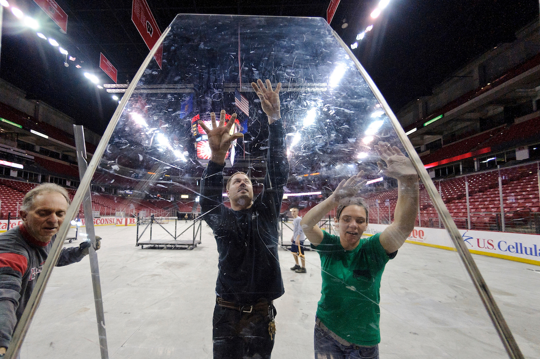 Staff members at the Kohl Center at the University of Wisconsin-Madison work to convert the arena space from a basketball court to an ice hockey rink