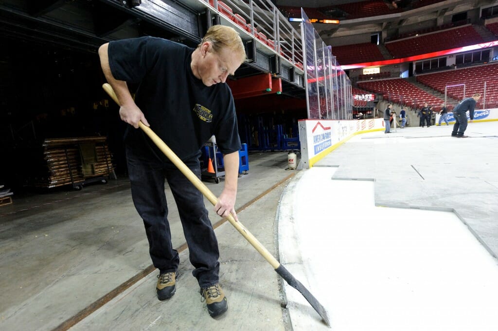 Staff members at the Kohl Center at the University of Wisconsin-Madison work to convert the arena space from a basketball court to an ice hockey rink