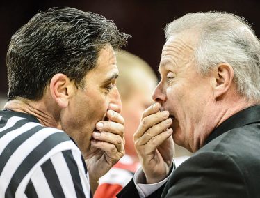 Bo Ryan chatting with the referee with hands over mouths