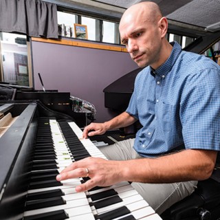 Christopher Taylor shows off the internal workings of the hyperpiano. The electronics inside the double- keyboard console connect to two separate pianos.