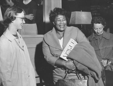 Black and white photo of Ella Fitzgerald with two students.