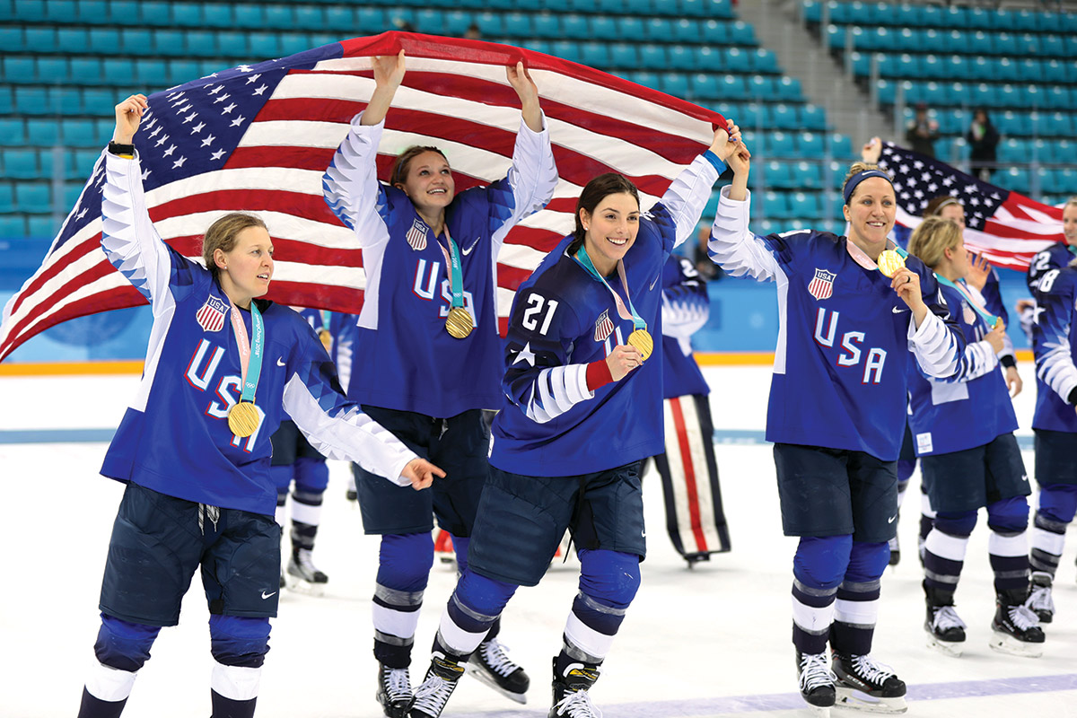 The USA Women's hockey team holds American flags and gold medals after a win at the Pyeongchang Olympics