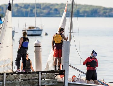 Members of the Hoofers Sailing Club bring their boats to a pier at the Memorial Union Terrace.