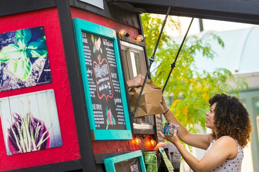 Woman accepts bag of food from food cart vendor