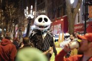 A person wearing a skeleton costume stands among other costumed party-goers on State Street in Madison, Wisconsin