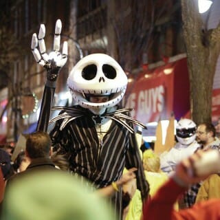 A person wearing a skeleton costume stands among other costumed party-goers on State Street in Madison, Wisconsin