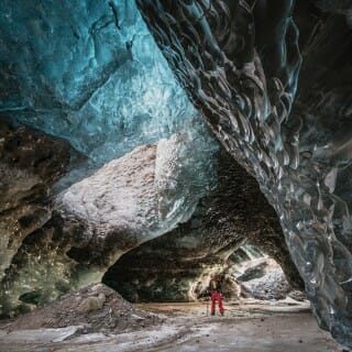 An explorer stands at the center of a gigantic ice cave in Iceland