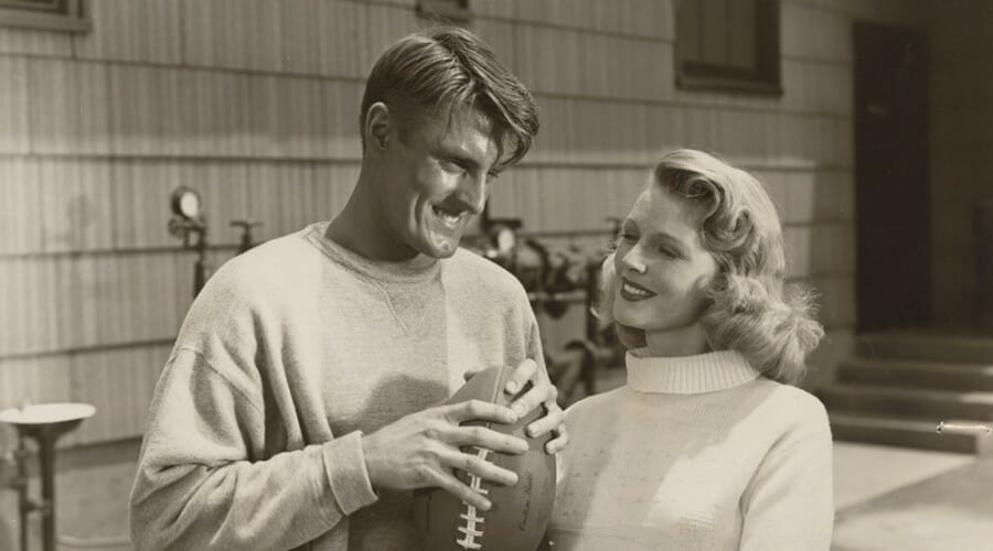 Elroy Hirsch holding a footbal and a female co-star in scene from movie, "Crazylegs"