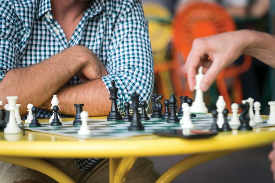 Close-up photo of two people's hands and a chessboard on the Memorial Union Terrace