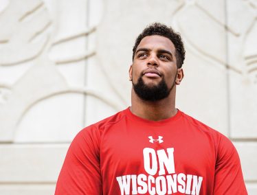 Portrait of Bryson Williams wearing a red shirt printed with words "On Wisconsin"