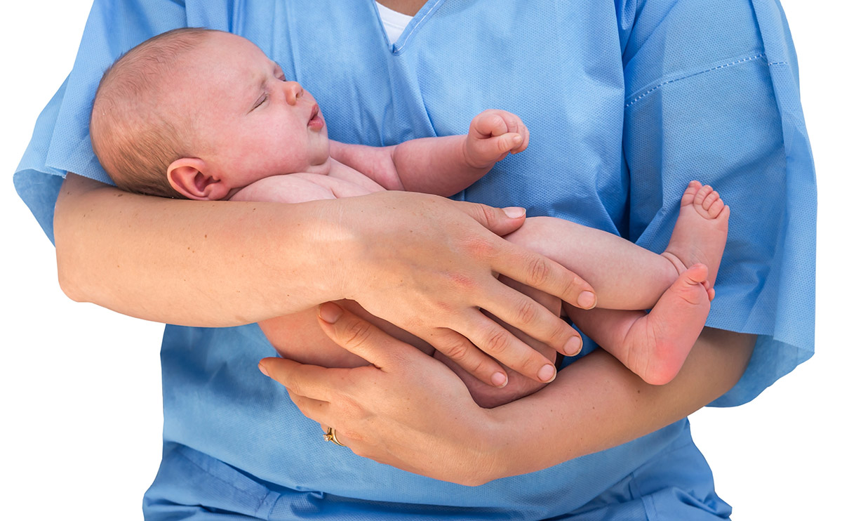 Photo of healthcare worker in scrubs holding a baby
