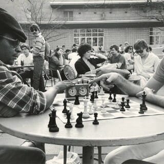 Black and white photo from the 1980s of two students playing a game of chess on the Memorial Union Terrace