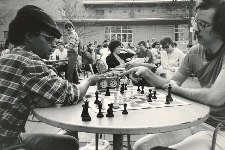 Black and white photo from the 1980s of two students playing a game of chess on the Memorial Union Terrace