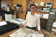 Nash Weiss poses with book of old newspapers