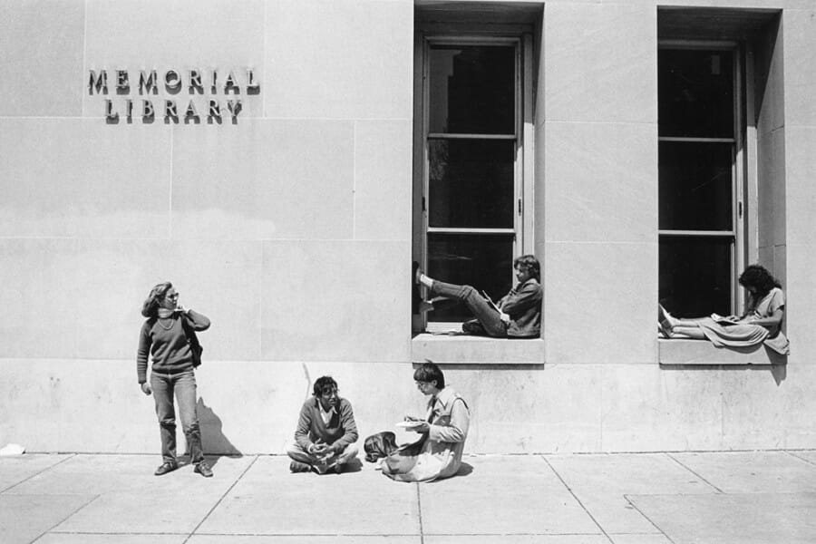 Black and white photo of students sitting outside of Memorial Library on the UW–Madison campus