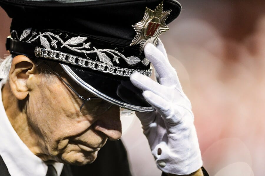 Mike Leckrone shown in close up wearing white glove and embellished director hat