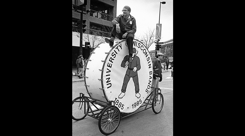 Mike Leckrone sits atop a large drum on wheels at the UW Homecoming Parade on October 1987