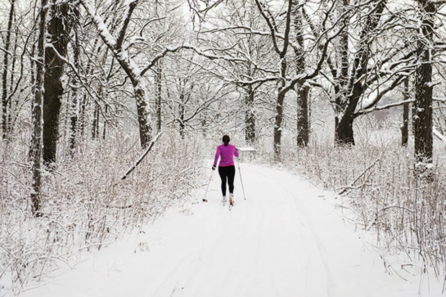 A woman skis down a snow-covered path in the UW Arboretum