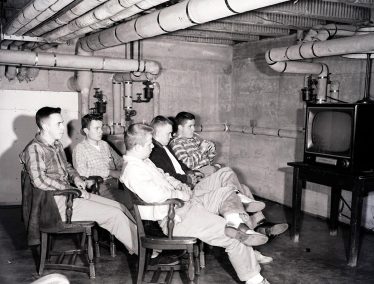 1955 black and white photograph of students wait in front of a television set in one of the men’s halls