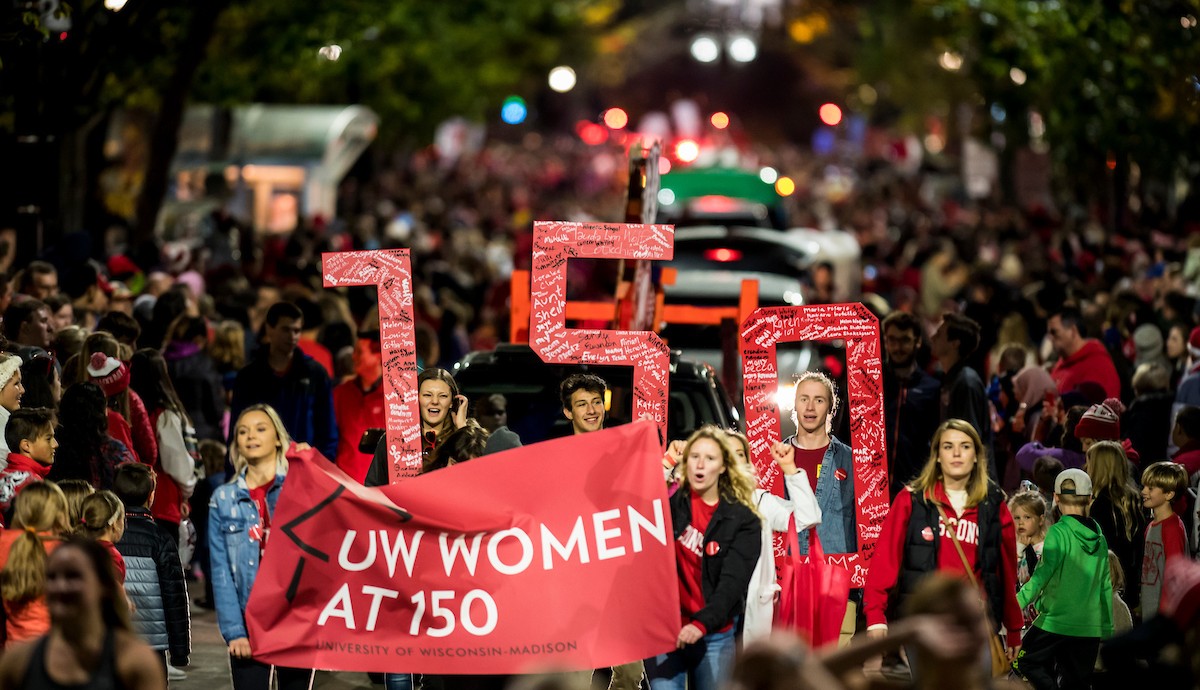 Students march in parade holding banner that reads "UW Women at 150"