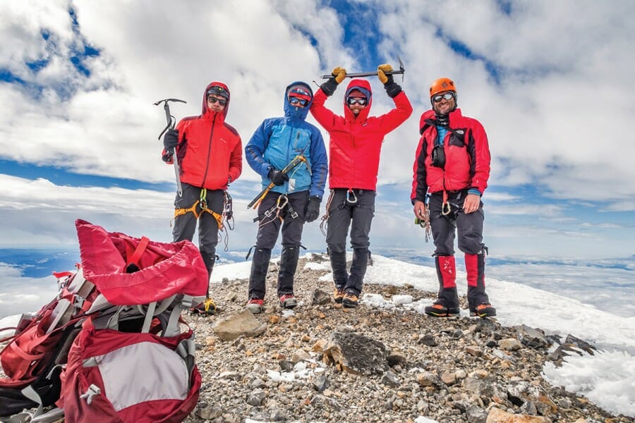 Daniel McKay and his climbing partners, Matt Baldwin, Patrick Johnston, and Rick Laverty, celebrate on the windy summit of Mount Rainier.