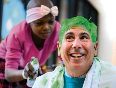 A child cancer patient spray paints David Margolis' hair green
