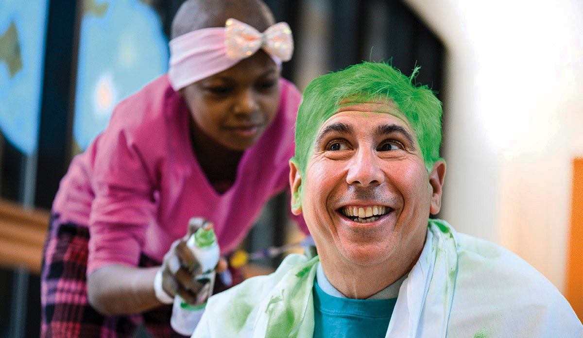 A child cancer patient spray paints David Margolis' hair green