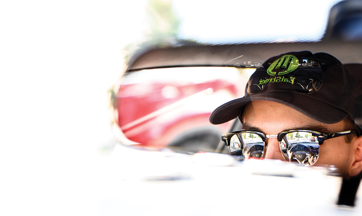 Face of delivery driver reflected in car rear view mirror