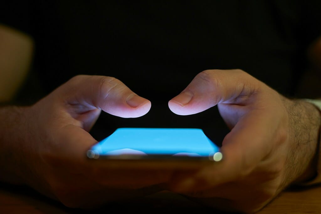 Close-up of hands holding a glowing smartphone