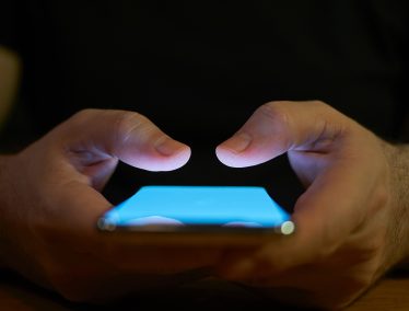 Close-up of hands holding a glowing smartphone