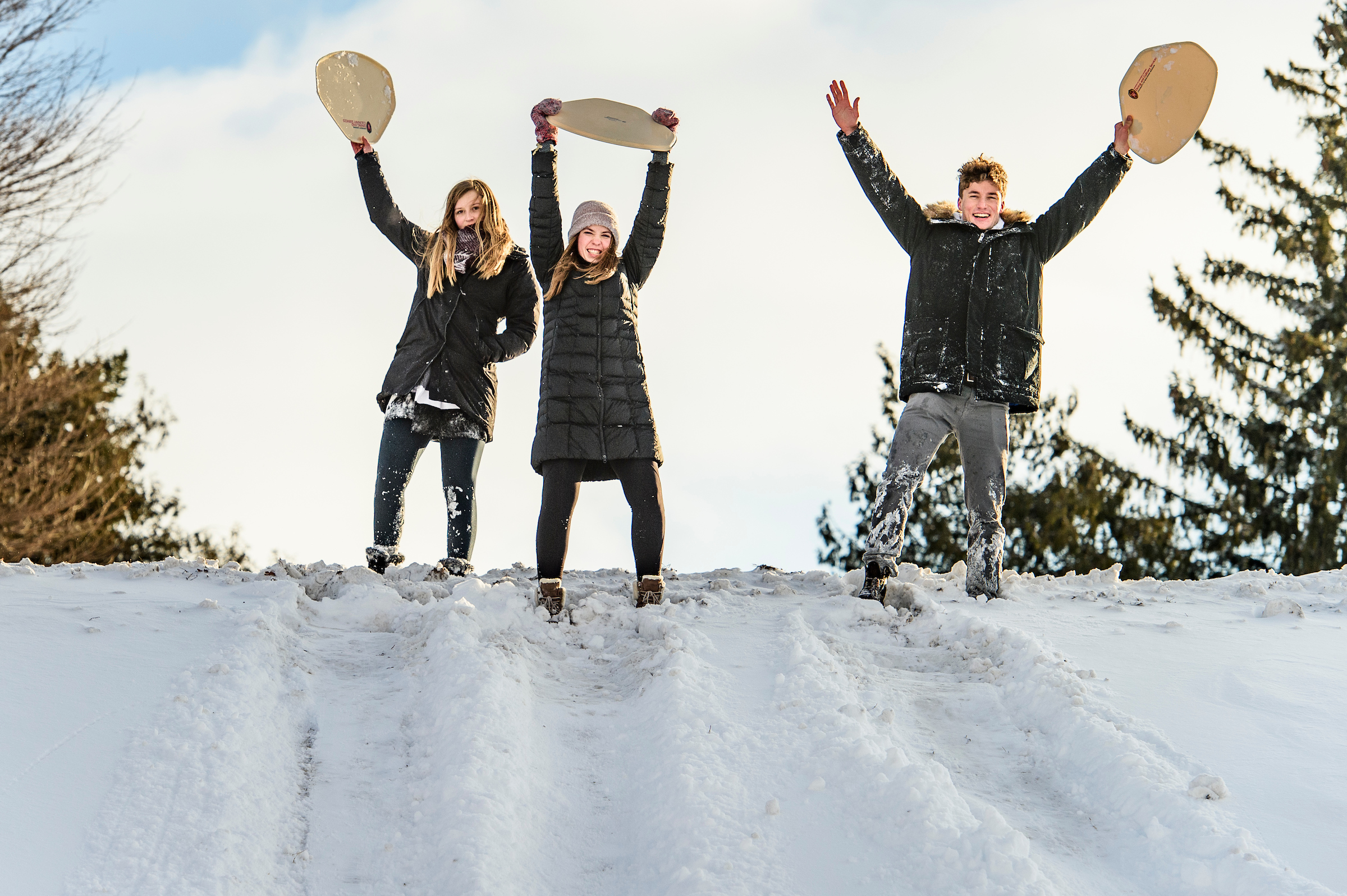 Students hold cafeteria trays above their heads as they prepare to sled down a snowy Observatory Hill