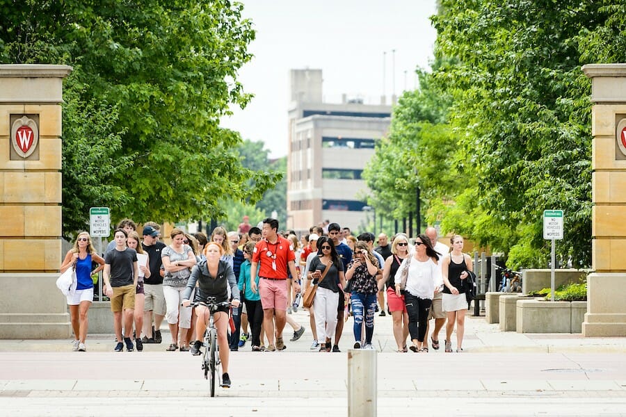 Student guides from Campus and Visitor Relations lead a group of visitors across University Avenue on a tour of the UW campus