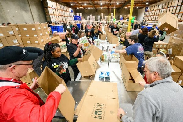 Volunteers from the University of Wisconsin–Madison and the University of Oregon pack boxes full of food in a warehouse