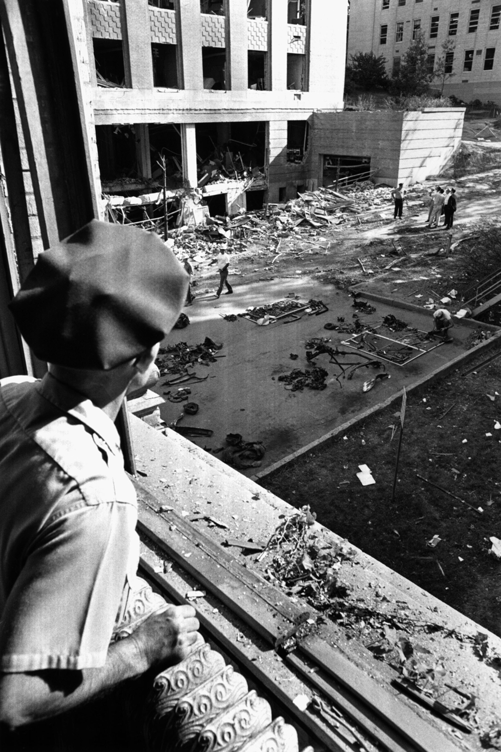 A police officer looks out over the Sterling Hall wreckage from a blown-out window