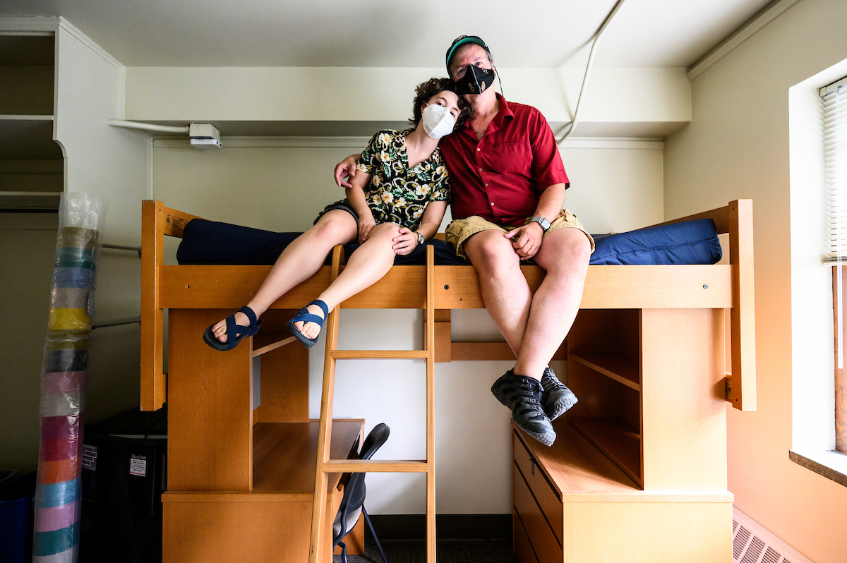 Todd Rosenberg and daughter Bella sit on her dorm room bunk bed, wearing face masks