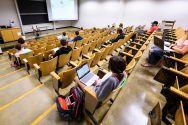 Students sit in a socially-distanced lecture hall