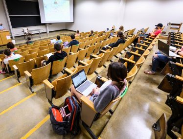 Students sit in a socially-distanced lecture hall