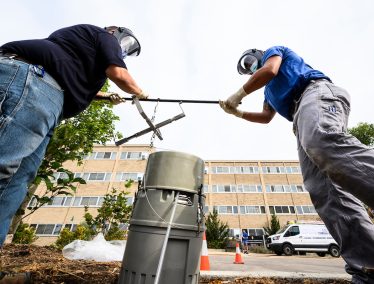 Campus plumbers retrieve a wastewater sample for testing.
