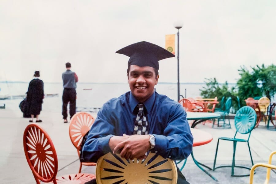 A young Raju sitting at the Memorial Union Terrace wearing a graduation cap