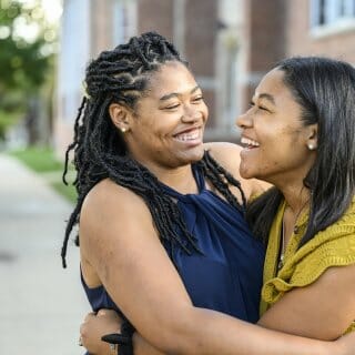 Sisters Eryne and Sydne Jenkins smile at one another as they embrace
