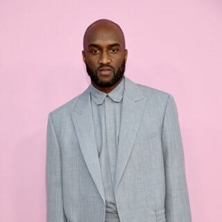 Virgil Abloh wearing a gray suit against a pink background
