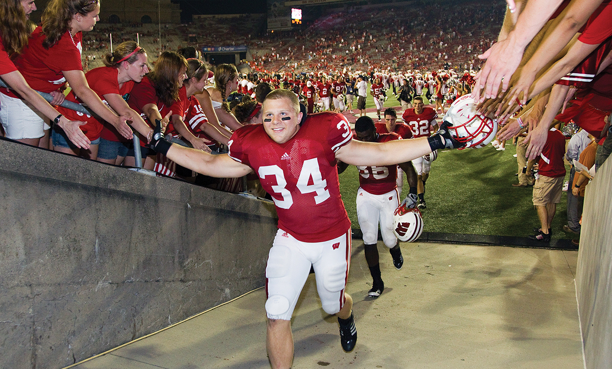 Bradie Ewing in his Badger football uniform exiting Camp Randall field while high-fiving fans
